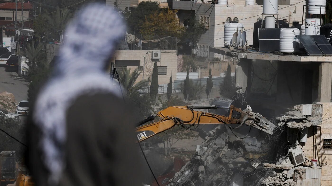 A man watches as Israeli forces demolish Palestinian homes near the Silwan neighbourhood in occupied East Jerusalem on 22 December 2025 (Ammar Awad/Reuters)