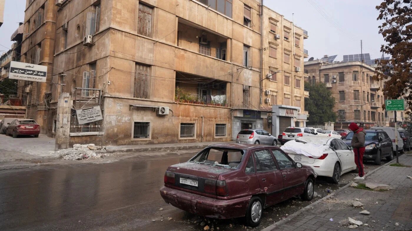 Damaged cars and building in Syria's northern city of Aleppo after Monday's wave of attacks between SDF and Syrian government forces on 23 December 2025 (Karam al-Masri/Reuters)