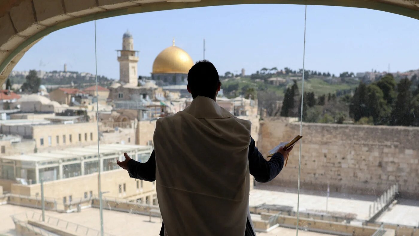 A Jewish worshipper prays facing the Al-Aqsa Mosque and the Western Wall during Passover ceremonies in Jerusalem's Old City, 6 April 2026 (Reuters/Ronen Zvulun)