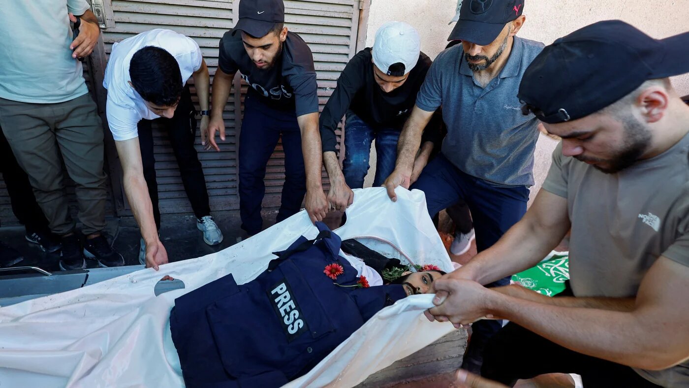 Mourners gather around the body of Al Jazeera Mubasher cameraman Ahmed Wishah, his press vest laid on the shroud, at Al-Aqsa Martyrs Hospital in Deir al-Balah, central Gaza Strip, on 21 June 2026