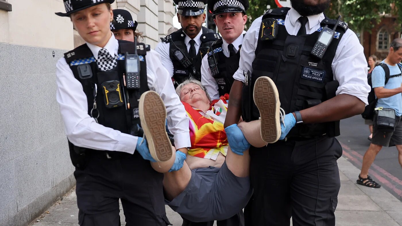 Police officers carry away a Palestine Action supporter outside Westminster Magistrates' Court in London on 30 July 2026, as hearings began for supporters accused under the Terrorism Act of displaying signs backing the banned group