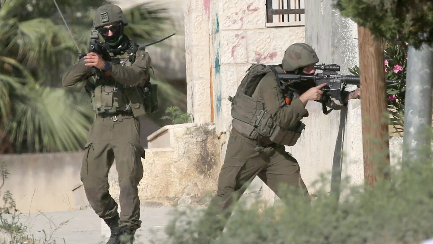 Israeli soldiers aim their weapons and take up positions towards Palestinians during the demolition of a home in Nablus on 11 August 2026 (Nasser Ishtayeh/SOPA Images via Reuters)