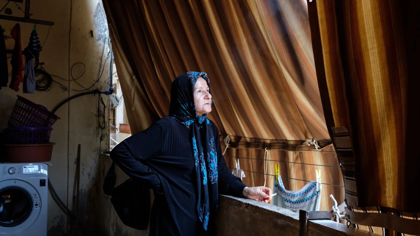 Fatima fume une cigarette sur son balcon à Hay el-Sellom pendant que son fils Ali dort dans l’appartement, le 6 juillet (MEE/Rita Kabalan)