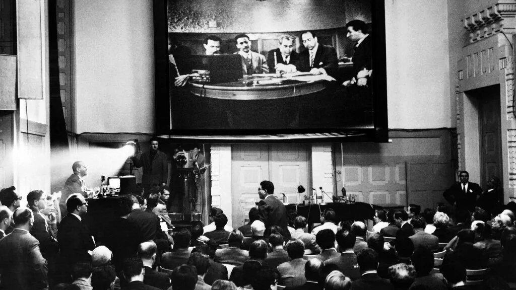 Des journalistes suivent la conférence de presse télévisée donnée le 24 mai 1961 par la délégation FLN présidée par Krim Belkacem à la Maison de la presse à Genève (AFP)