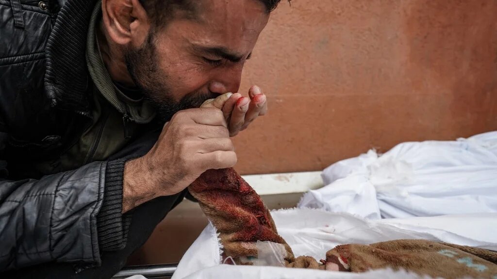 A Palestinian man mourns over the body of a relative killed in Israeli strike at the Nasser hospital in Khan Younis in the southern Gaza Strip on 28 December 2023 (AFP)