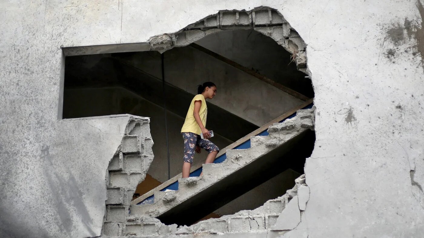 A Palestinian woman inspects a house damaged by an Israeli airstrike in Al-Zawayda, central Gaza, after evacuation warnings, 11 October 2026 (Eyad Baba/AFP)