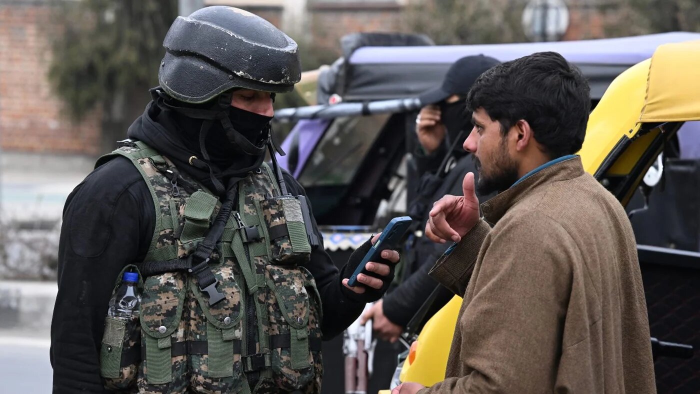 A Special Operations Group officer of the Indian police checks a pedestrian’s mobile phone in Srinagar, Kashmir, ahead of India’s Republic Day on 22 January 2026 (Tauseef Mustafa/AFP)