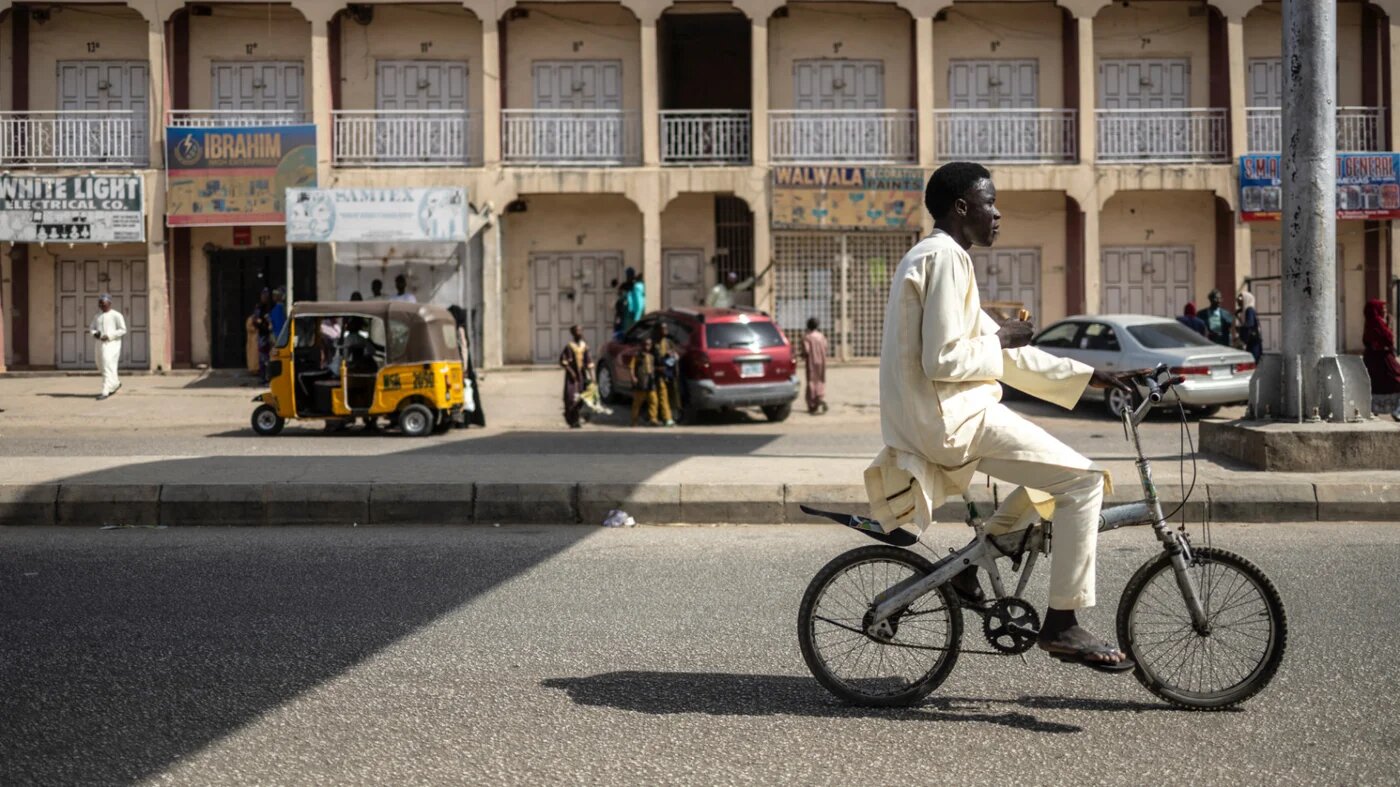 A man drives a bicycle near Kano Pillars Stadium after the Eid al-Fitr prayer, Nigeria, 30 March 2025 (AFP)