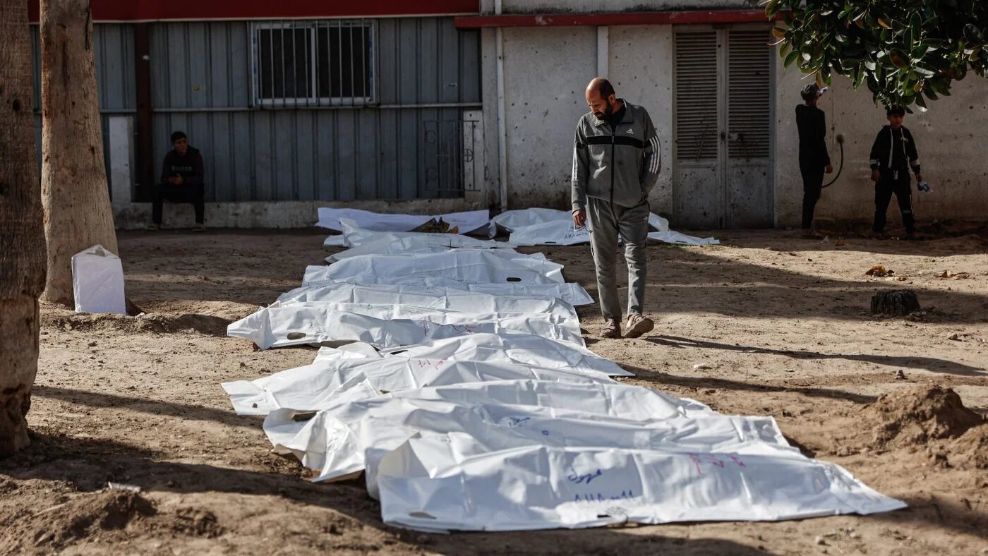 A man looks at body bags containing human remains after civil defence teams exhumed graves at Al-Ahli Arab Baptist Hospital in Gaza City, 7 December 2025 (AFP)