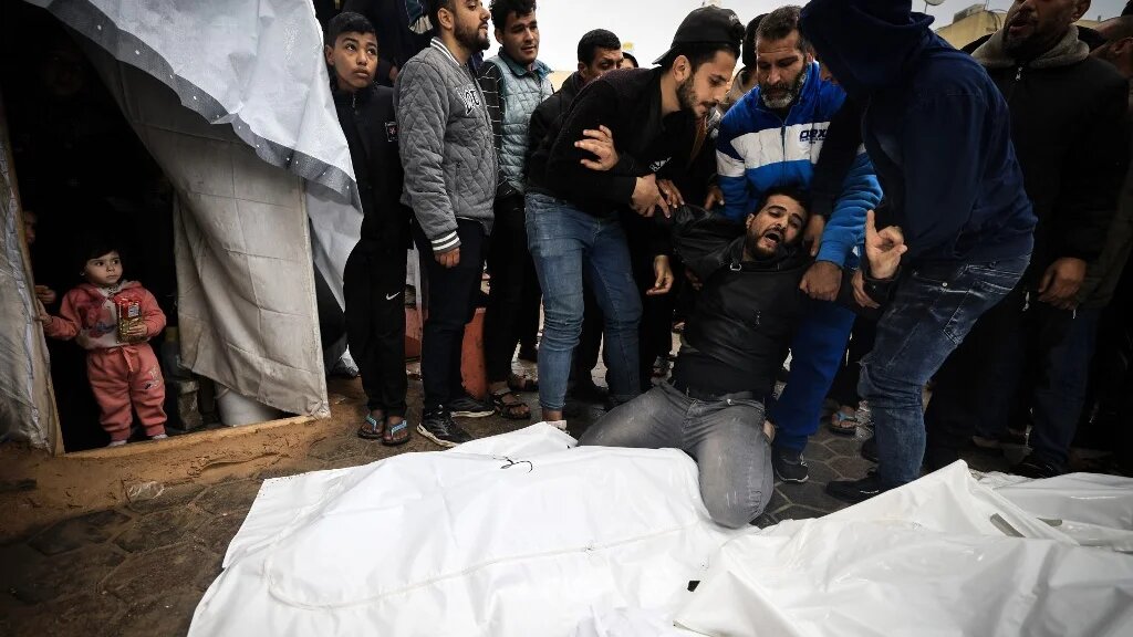 A man mourns relatives killed in an Israeli strike on the Maghazi refugee camp in the central Gaza Strip, 25 December 2023 (Mahmud Hams/AFP)