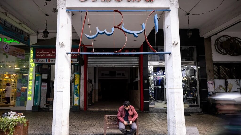 A man sits at the entrance of the ABC cinema, in the western Moroccan city of Casablanca, 24 January 2022 (AFP)