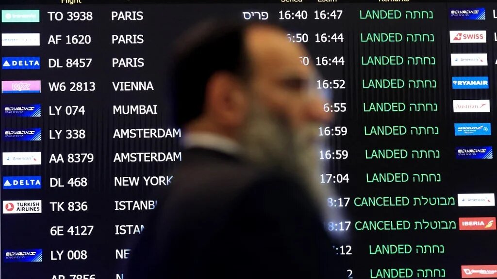 A man walks past a screen announcing arrivals at Israel's Ben Gurion airport on 4 March 2020 (AFP)