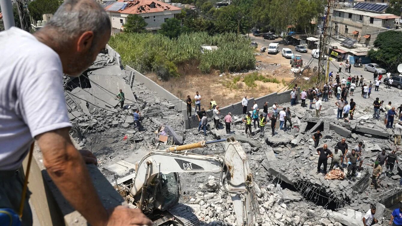 A man watches as heavy machinery, first responders and residents search the site of an Israeli air strike in Deir al-Zahrani, southern Lebanon, on 15 August 2026 (Abbas Fakih/AFP)