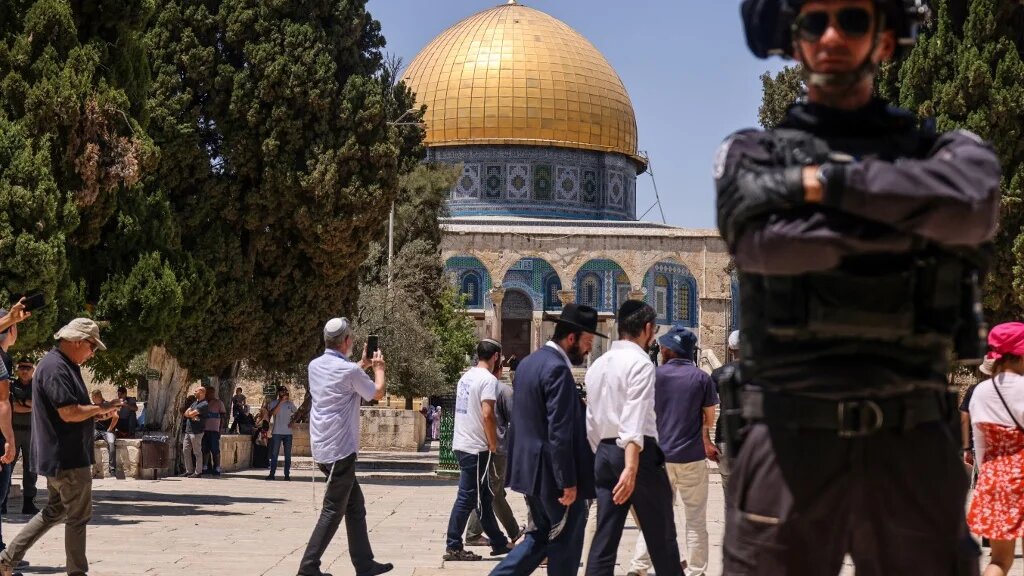  A member of Israeli security forces stands guard, as a group of Jewish settlers enter the al-Aqsa mosque compound in occupied East Jerusalem, 18 July 2021 (AFP)