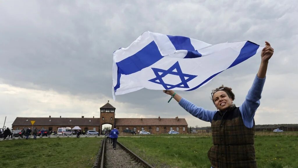 A participant holds up the Israeli flag at The March of the Living at the site of the former Auschwitz-Birkenau camp in Poland to honour the victims of the Holocaust, 28 April 2022 (AFP)