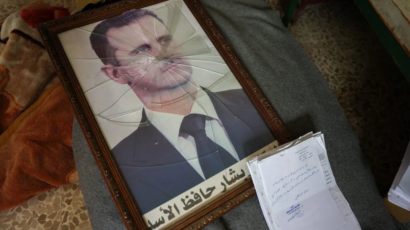A portrait of Syrian President Bashar al-Assad with its frame broken at a Political Security Branch facility on the outskirts of Hama, 7 December 2024 (Omar Haj Kadour/AFP)