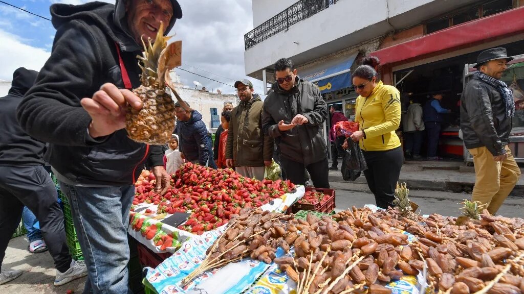 A street vendor holds up a pineapple at a market in Ariana, near the capital Tunis, on 2 April 2022 (AFP)