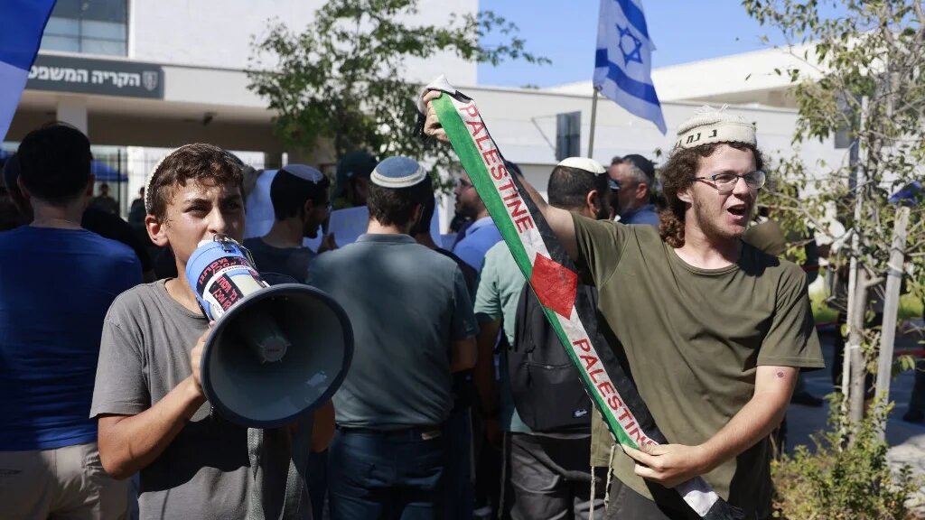 Right-wing Israeli holds a Palestine scarf at a protest against the questioning of military reservists suspected of abuse of a Palestinian detainee, outside military court in Beit Lid army base near Kfar Yona on July 30, 2024 (AFP)