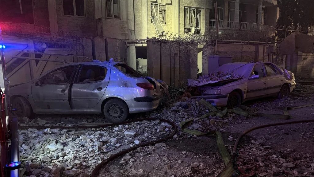 Destroyed vehicles are pictured outside a building that was hit by an Israeli strike in Tehran on 13 June 2025 (Meghdad Madadi/Tasnim News/AFP)