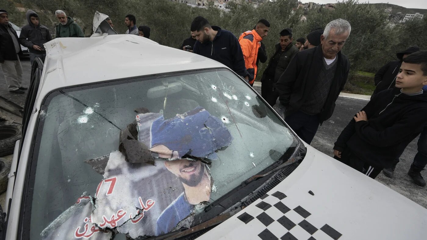 Palestinians inspect a car in which two men were shot dead by Israeli forces in the occupied West Bank village of Jaba on 14 January 2023 (AP)