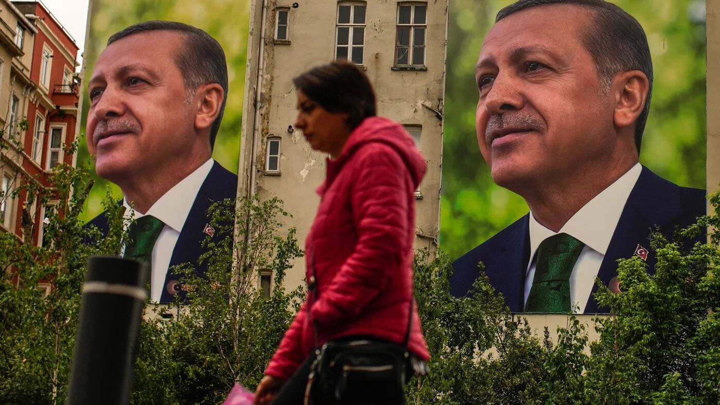 A person walks past billboards of Recep Tayyip Erdogan a day after the presidential election day, in Istanbul, 15 May (AP)