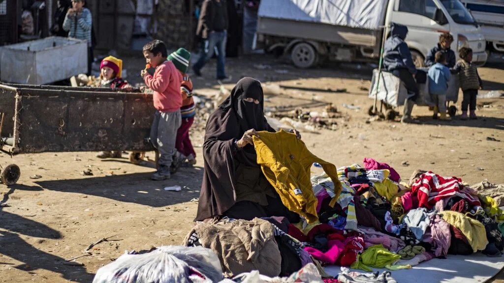 A woman sorts used clothing on the ground at the Kurdish-run al-Hol camp in northeastern Syria on 14 January (AFP/File photo) 