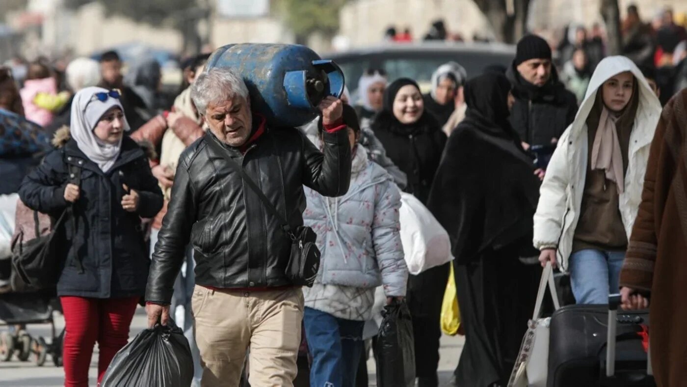 Residents carry their belongings as they flee Aleppo's Ashrafieh Kurdish neighbourhood on 7 January 2026 (Bakr Alkasem/AFP)