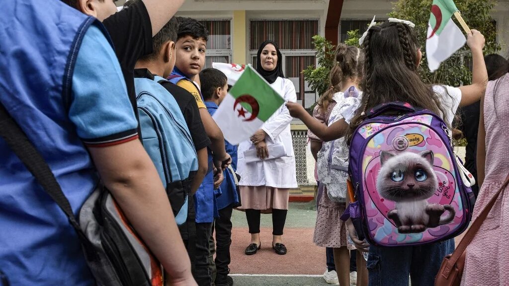 Students wave Algerian national flags during the morning assembly on the first day of school in Algiers, on 19 September 2023 (AFP)