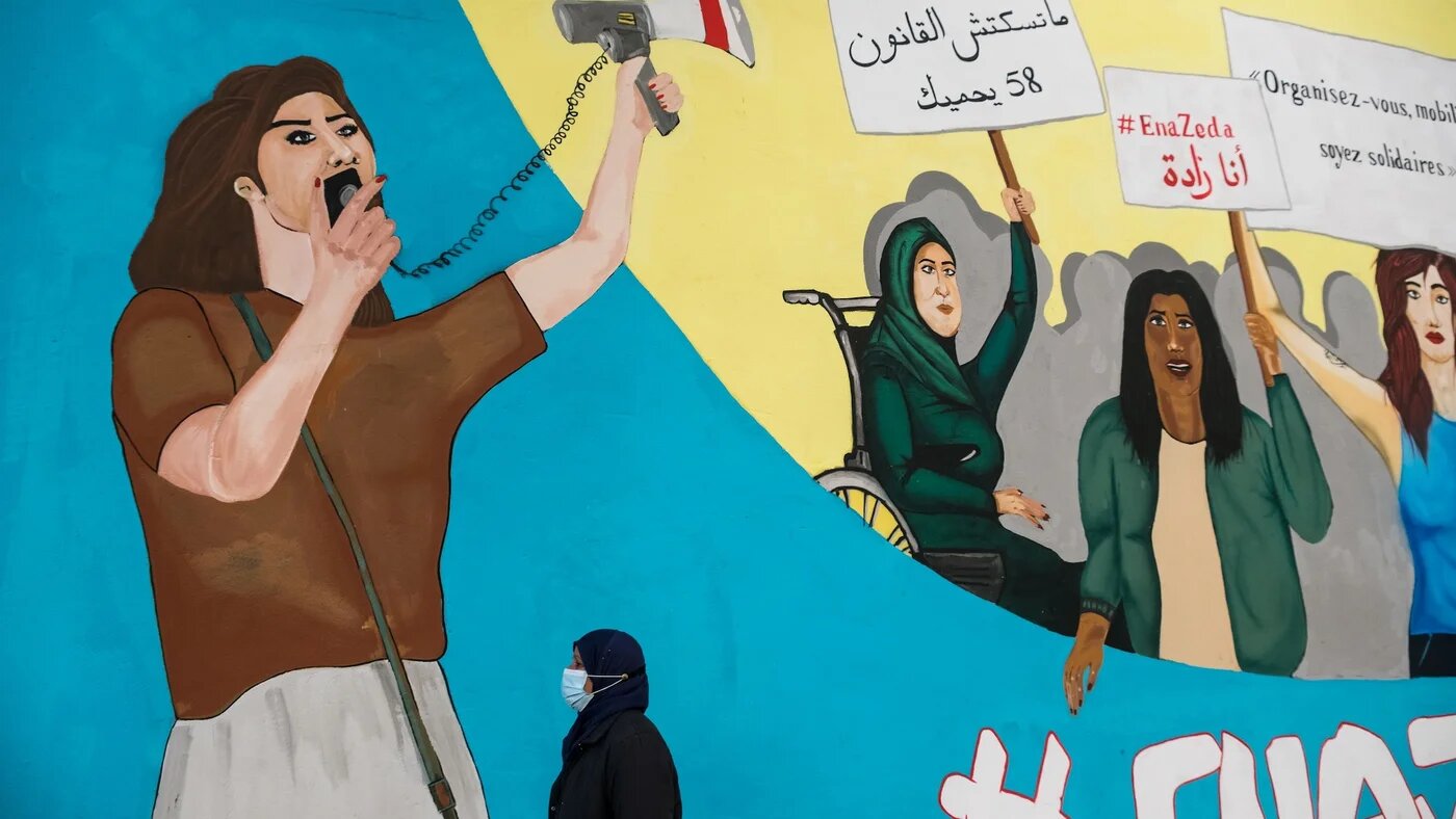 Une Tunisienne passe devant une peinture murale réalisée par l’ONG Aswat Nissa, dans le centre de Tunis, en janvier 2021 (MEE/Constantin Gouvy)