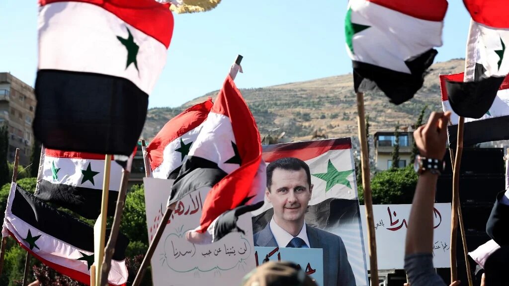 People wave Syrian national flags and pictures of President Bashar al-Assad
