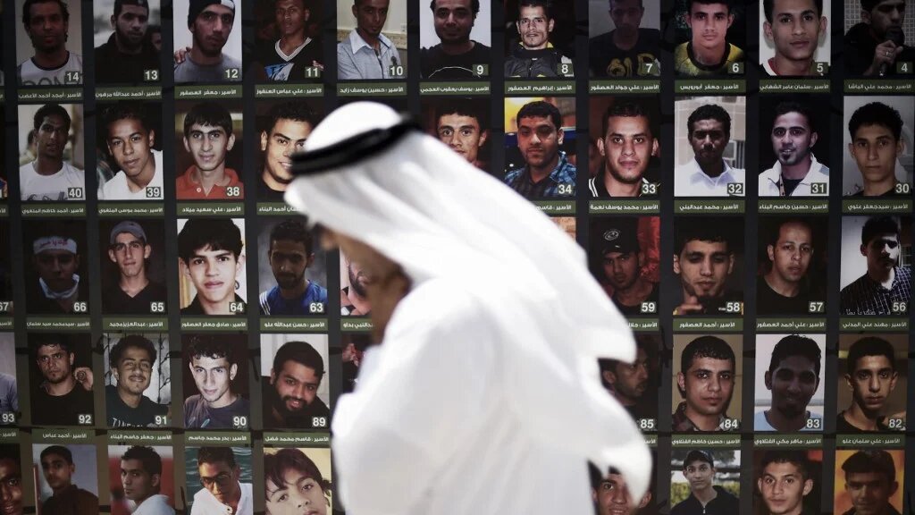 A Bahraini man walks past portraits of men reportedly detained after attending anti-government protests