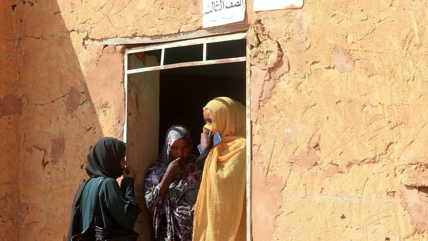 Three women, who are part of a group of displaced people from the towns of Bara and Umm Dam Haj Ahmed in North Kordofan, take shelter in Omdurman on 10 November 2025 (Ebrahim Hamid/AFP)