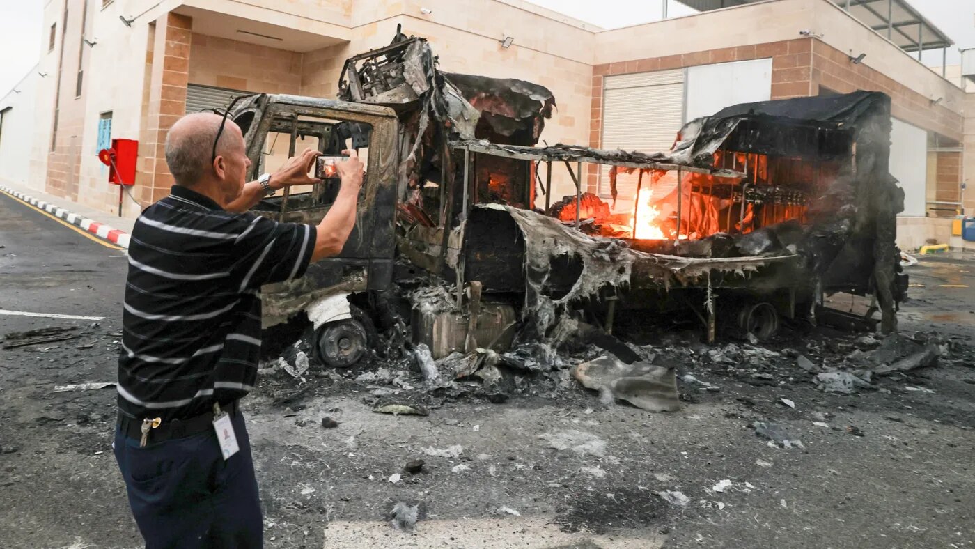 A Palestinian man records a burning truck with his phone after an Israeli settler attack in Beit Lid, east of Tulkarm in the occupied West Bank on 11 November 2025 (AFP/Jaafar Ashtiyeh)