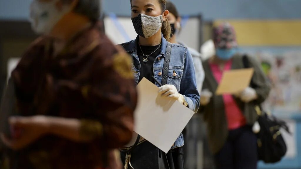 People wait in line to hand in their ballots to election officials after voting at a YMCA in Chinatown during the Massachusetts State Primary on 1 September in Boston