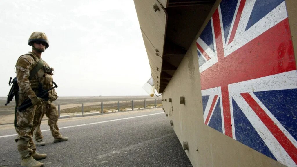 British soldiers keep watch as a tank passes ahead of the security transfer between British and Iraqi troops in Basra on 16 December 2007