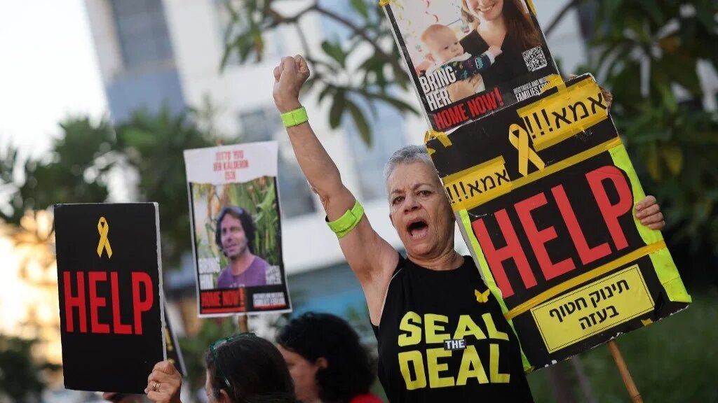 A protester carries a poster during a gathering calling for the release of Israeli captives in Tel Aviv on 19 August 2024 (Jack Guez/AFP)