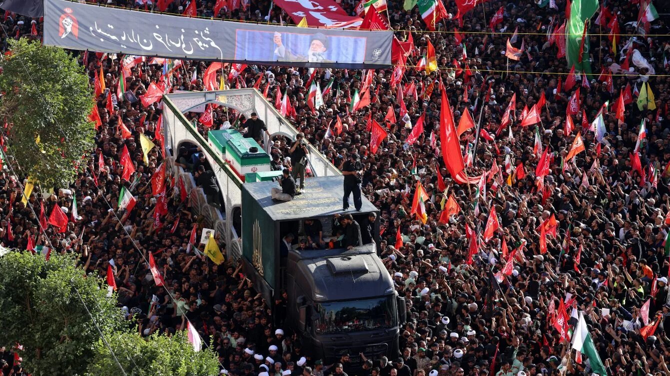 Crowds of mourners surround the convoy carrying the coffins of Iran’s late supreme leader Ali Khamenei and his family members during a funeral procession in Mashhad, 9 July 2026 (Atta Kenare/AFP)
