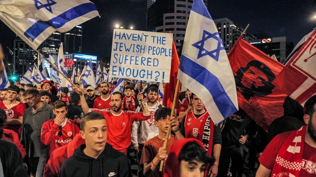 Demonstrators march with signs and Israeli flags during a rally against the government's judicial reform bill in Tel Aviv on 1 April 2023 (AFP)