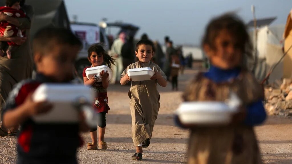 Displaced Syrian children with boxes of food distributed by a local charity, before the Iftar meal during Ramadan, at a camp for displaced people in Syria's northwestern Idlib province, 3 April 2022 (AFP)