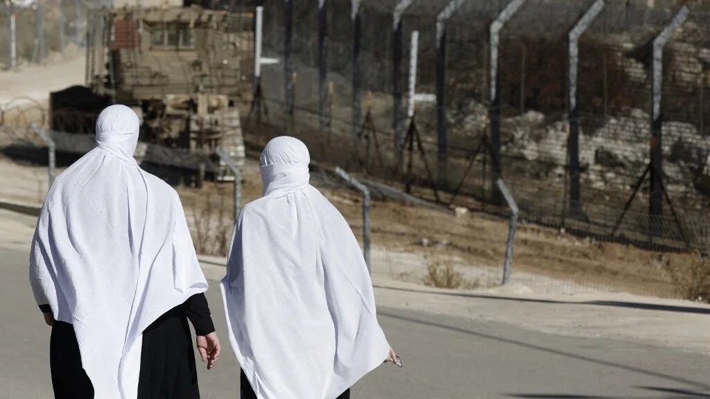 Druze women near the fence leading into the UN-patrolled buffer zone, which separates Israeli and Syrian forces on the Golan Heights, near Majdal Shams, 15 December 2024 (Jalaa Marey/AFP)
