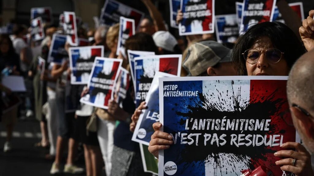 Protesters hold placards which read 'Anti-Semitism is not residual' as they gather to condemn the alleged anti-semetic gang rape of a 12 year-old girl, in Lyon, France, on 19 June 2024 (Jean-Philippe Ksiazek/AFP)