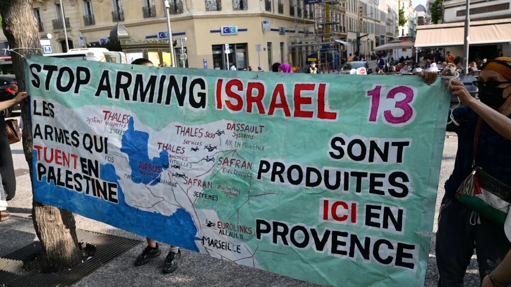 Demonstrators install a banner reading "The weapons killing in Palestine are produced here in Provence" at a gathering against a shipment of Eurolink military equipment parts set to go to Israel, in Marseille on 5 June (Christophe Simon/AFP)