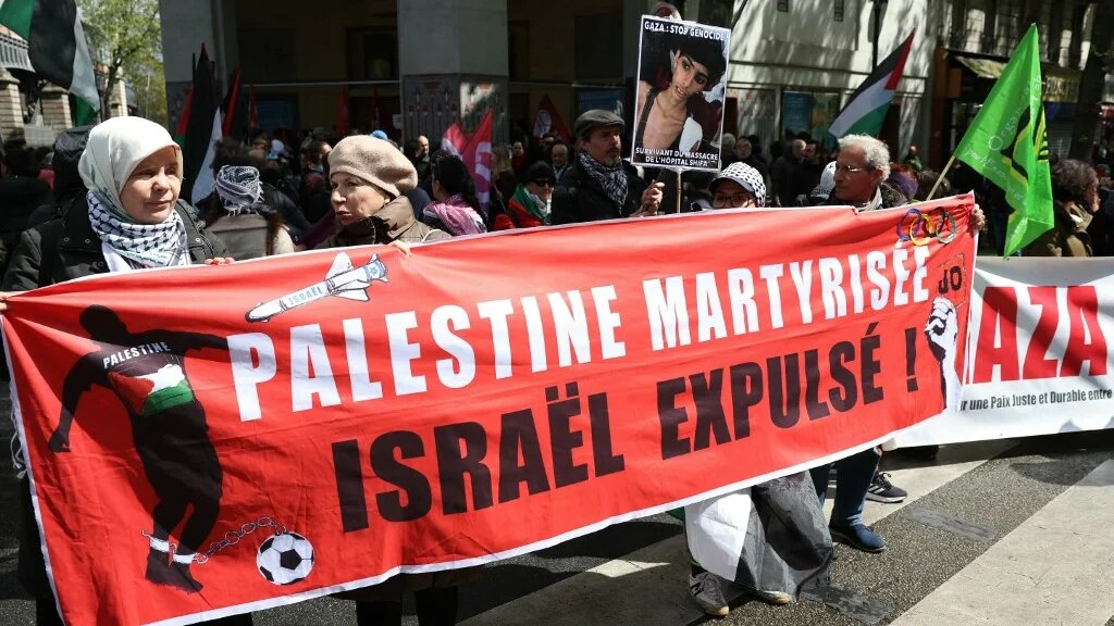 Demonstrators hold a banner reading “Martyrised Palestine, Israel expelled, JO [Olympic Games]” during a protest “against racism and Islamophobia” at the call of various organisations in Paris on 21 April (Alain Jocard/AFP)