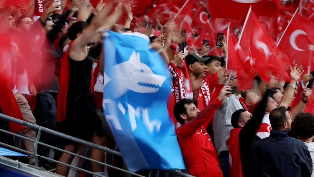 A participant standing among Turkey supporters waves the flag of Turkish ultra-nationalist group Grey Wolves prior to the UEFA Euro 2024 round of 16 football match between Austria and Turkey at the Leipzig Stadium in Leipzig, eastern Germany on July 2, 2024.  (Ronny Hartmann/AFP)