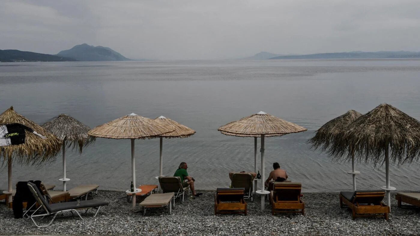Des touristes fréquentent un café en bord de mer sur l’île grecque d’Eubée, le 5 mai 2021 (AFP)