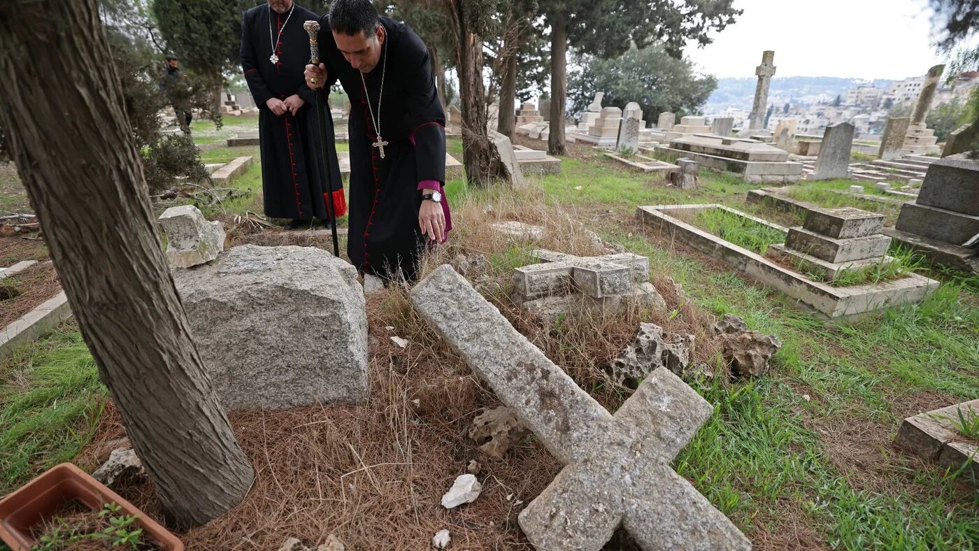 Hosam Naoum, archbishop and caretaker of the Protestant cemetery, inspects vandalised graves on Mount Zion outside Jerusalem's Old City, 4  January 2023 (AFP) 