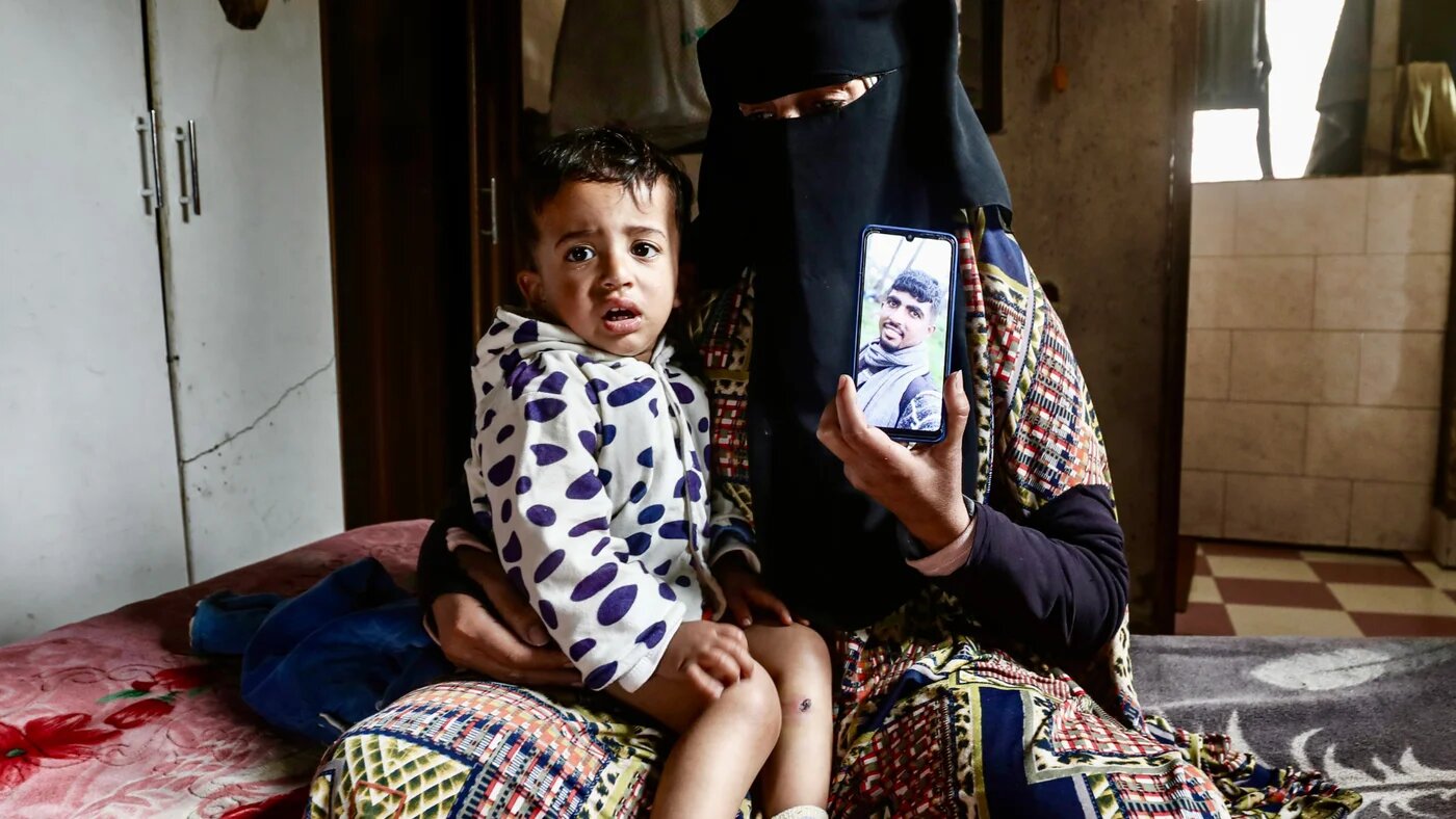 Jawad Abu Nassar, aged 21 months, sits on his grandmother's lab, as she hold a photo of her son, Osama on the phone, in the Gaza Strip, 24 March 2026 (MEE/Moiz Salhi)