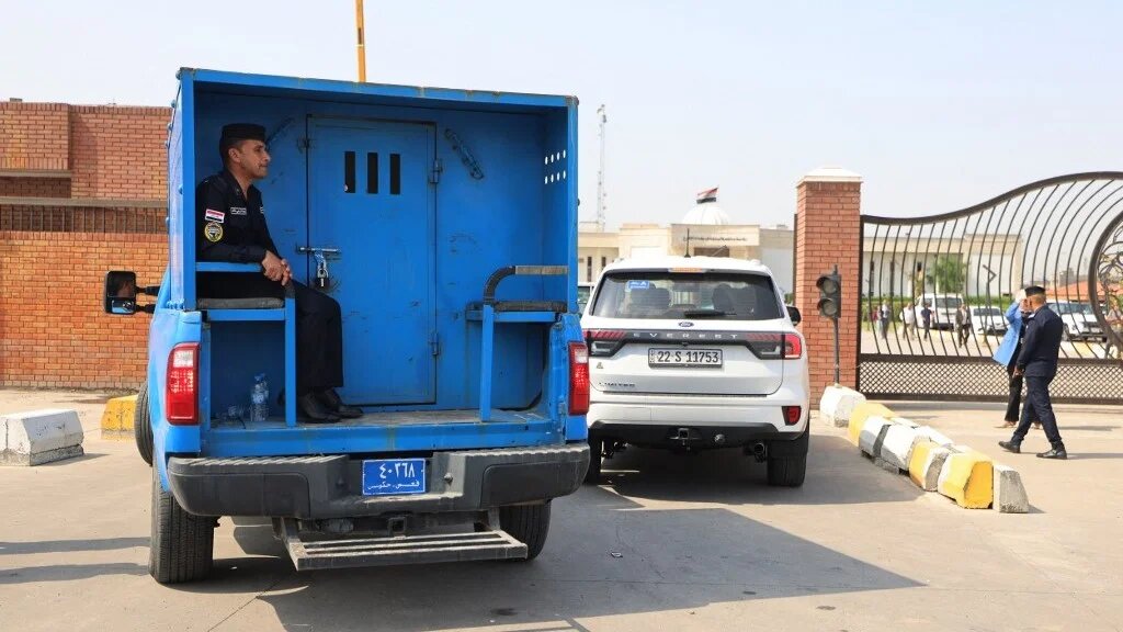 An Iraqi police patrol transports Iraqi detainees into the grounds of the Karkh Courthouse in the capital Baghdad on October 5, 2026 (Ahmad al-Rubaye/AFP)