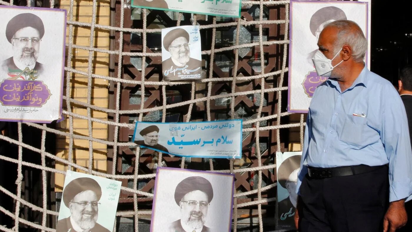 Un homme passe devant des affiches du candidat présidentiel Ebrahim Raïssi lors d’un meeting électoral à Téhéran, le 10 juin 2021 (AFP)