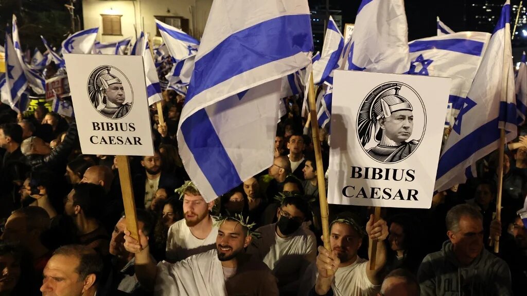 Israeli protesters carry placards depicting Benjamin Netanyahu as Julius Caesar during a demonstration against his new hard-right government, Tel Aviv, 21 January 2023 (AFP)